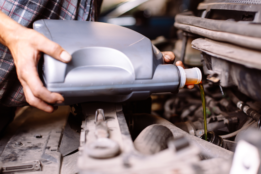 Man changing car oil to improve gas mileage