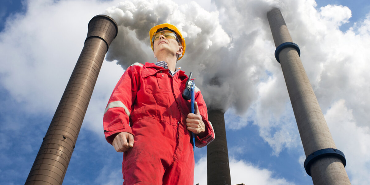 Engineer outside looking up at emissions from power plant.